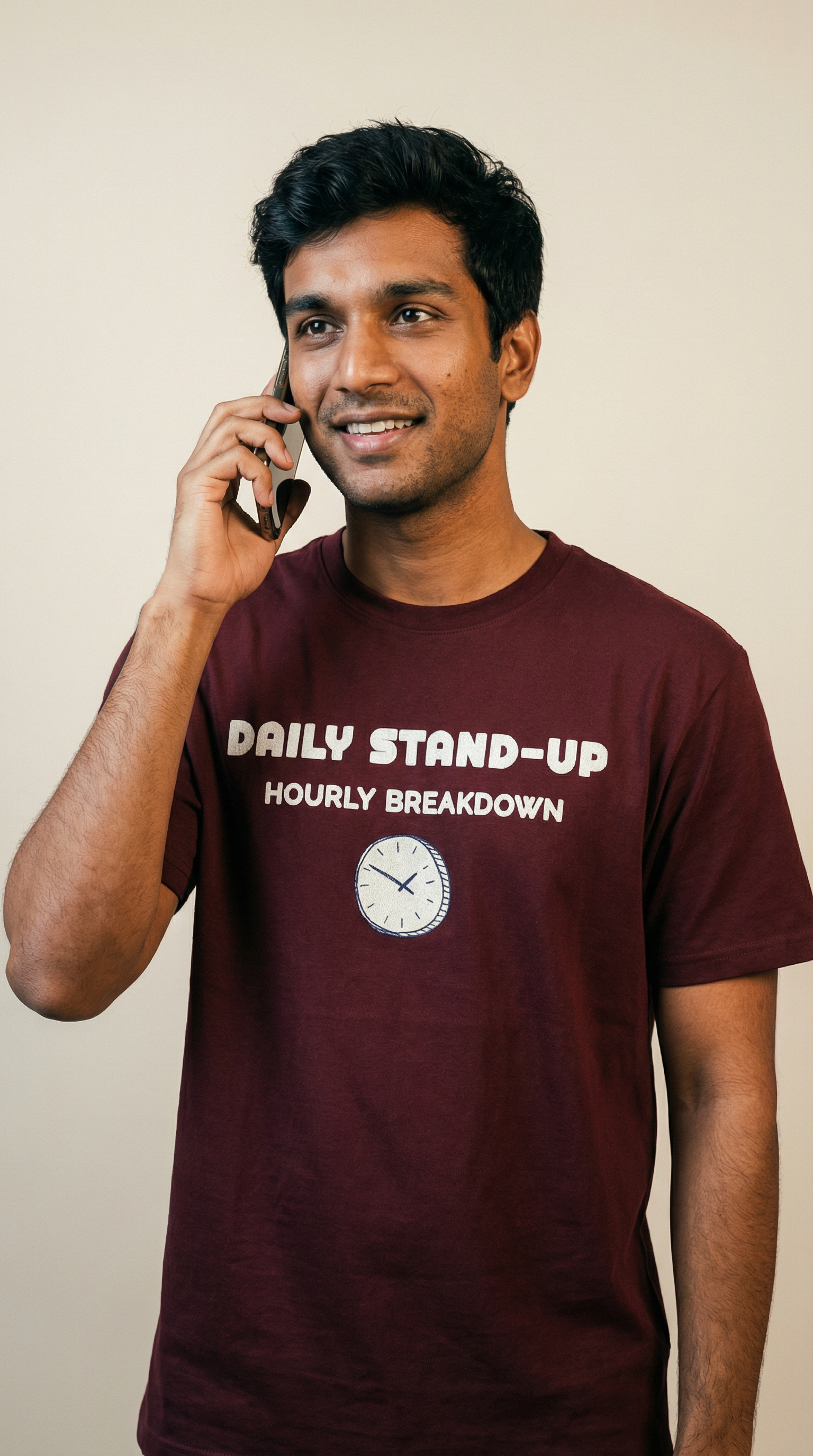 Man wearing a maroon t-shirt with text and a clock graphic, talking on a phone.