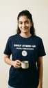 Person wearing a navy blue t-shirt with text and holding a mug against a plain background