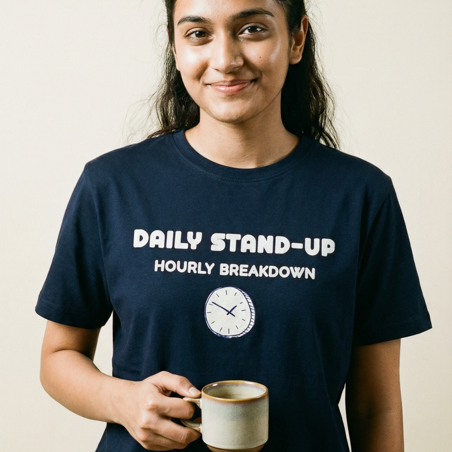 Person wearing a navy blue t-shirt with text and holding a mug against a plain background