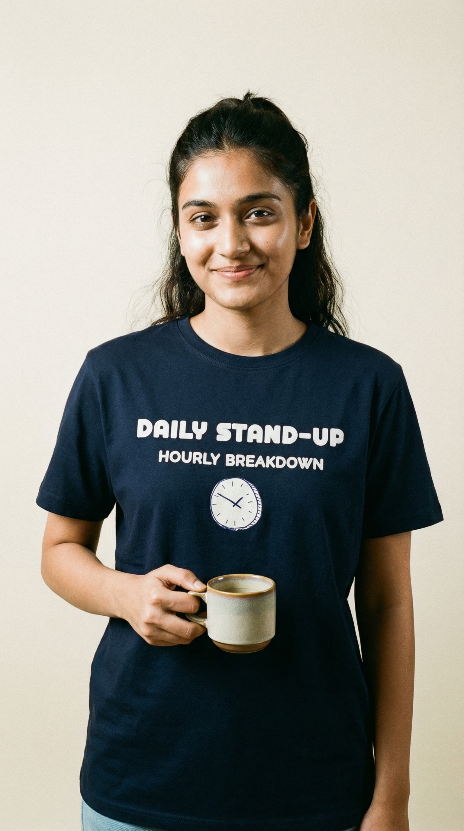 Person wearing a navy blue t-shirt with text and holding a mug against a plain background