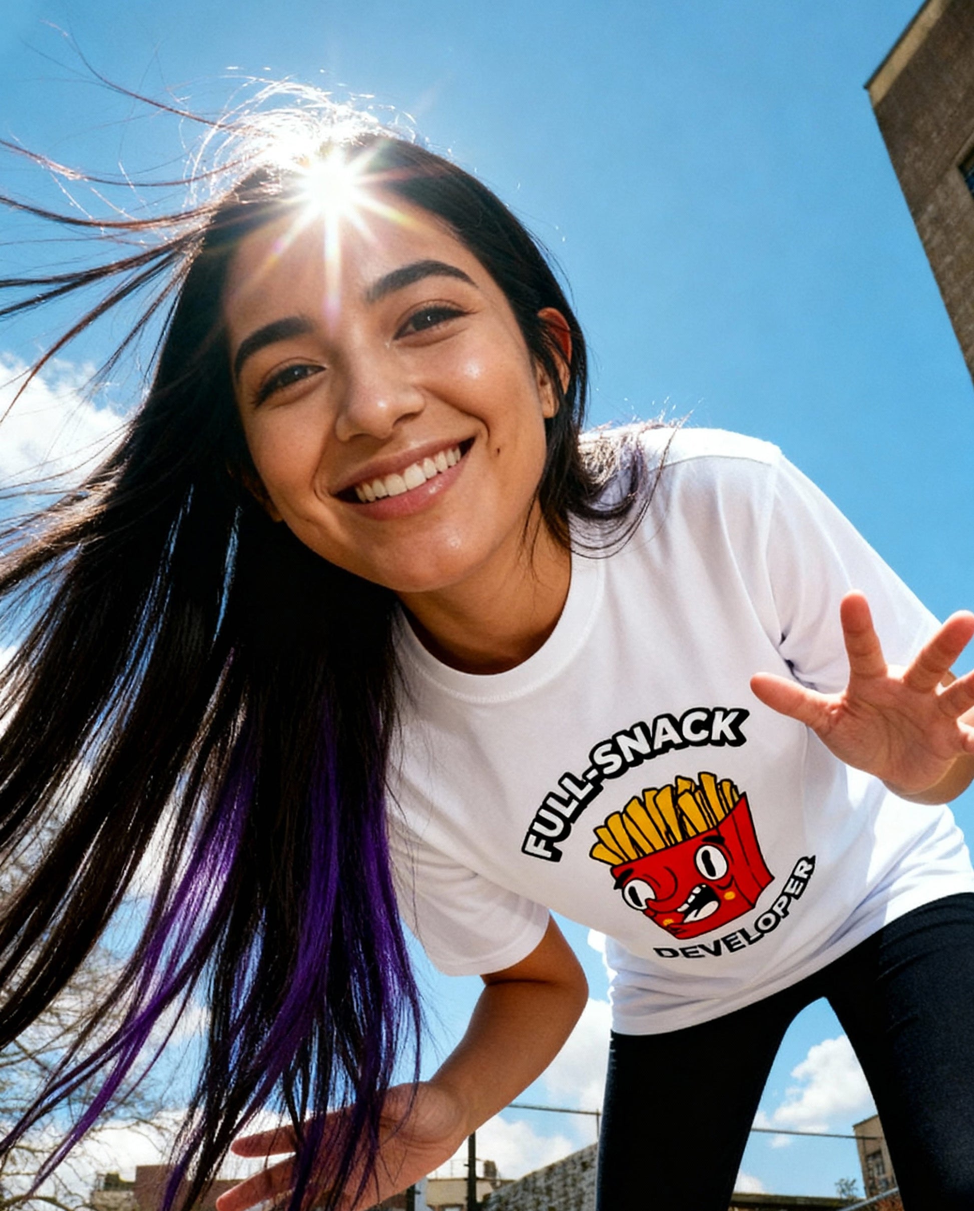 Person wearing a white t-shirt with a graphic design, standing outdoors on a sunny day.